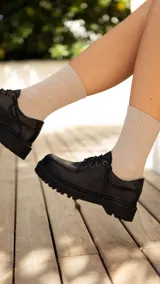 Zapato acordonado de cuero negro con suela track.