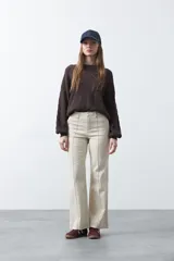 Pantalón de mujer color beige, de corte recto y tiro alto, con costuras frontales marcadas que recorren la pierna.