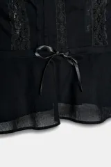 Top negro de escote cuadrado y tirantes anchos, con detalle de bordados florales y puntilla combinada a tono. Presenta una cintura ajustable con lazo frontal.