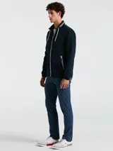 Campera rompevientos azul marino con cierre frontal, cuello alto con doble raya blanca, capucha oculta, puños elásticos y bolsillos con cierre.