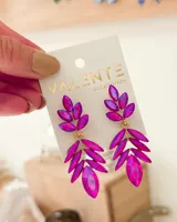 Aros colgantes con forma de hojas, compuestos por gemas facetadas color fucsia y engarce dorado.