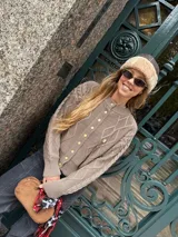 Saco tejido de punto con diseño de ochos y trenzas, color azul marino. Presenta cierre frontal con botones en contraste de color turquesa y un delicado bordado a mano en el pecho.