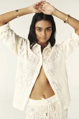 Camisa color blanco hueso con cuello clásico, tapeta con botones en la parte delantera y corte recto ligeramente oversize. Diseño con acabado de encaje.