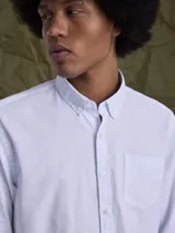 Camisa de manga larga confeccionada en tejido Oxford de algodón, con cuello abotonado y bolsillo frontal en el pecho.