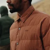 Campera puffer color naranja con cuello camisero, cierre con botones a presión, dos bolsillos de parche con botón en el pecho y relleno de pluma.