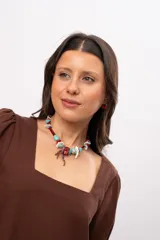 Collar corto elaborado con cuentas de turquesa reconstituida, piezas de nácar blanco, cuentas de cristal rojo y turquesa, y un dije central con forma de rama de coral.