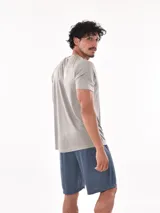 Remera deportiva de manga corta, color gris claro con sutil textura de rayas horizontales. Presenta cuello redondo y costuras reforzadas en los hombros.