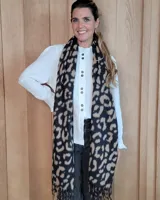 Bufanda de gran tamaño con estampado animal print en tonos negro y beige, con terminación de flecos en los extremos.