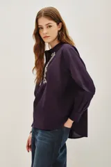 Camisa de algodón color blanco, con cuello redondo, cierre frontal parcial con botones y detalle de bordado con canutillos en el frente.