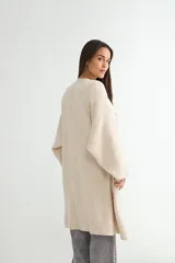 Saco tipo cárdigan largo de tejido de punto, color beige, con diseño abierto sin botones, mangas largas amplias y corte recto.