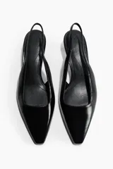Zapatos destalonados negros de tacón kitten, con punta fina, tira elástica en el talón y acabado brillante.