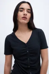 Remera negra con escote en V, cartera de botones, frunces y mangas cortas.