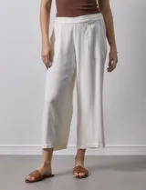 Pantalón de lino color crudo, de corte ancho y largo cropped, con bolsillos laterales.