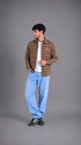 Camisa de manga larga con estampado de cuadros en tonos verdes, naranjas y marrones. Presenta cuello clásico, cierre frontal con botones y un pequeño bordado en el pecho.