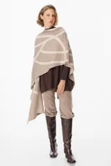 Ruana de tejido de punto con diseño geométrico de líneas curvas en tonos beige y visón. Presenta una caída fluida y envolvente, ideal para usar como capa sobre otras prendas.