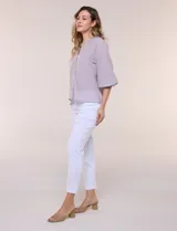 Blusa de gasa de color lila con calce holgado, cuello a la base con escote en V y cartera de botones a tono. Cuenta con fruncidos en el cuello y hombros que otorgan volumen, manga tres cuartos estilo abullonado con puño elastizado y ruedo suavemente redondeado.