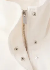 Anorak de estilo utilitario en color crudo, con cuello alto tipo embudo, cierre frontal con cremallera y botones a presión, y múltiples bolsillos de parche con solapa. Presenta un diseño oversize de manga larga.