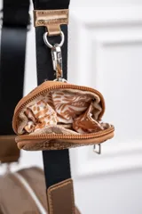 Bandolera color bronce con diseño acolchado, correa de tela regulable en color negro y monedero colgante con estampado de piel de serpiente.