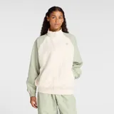 Campera deportiva New Balance, modelo WJ53517GAS, con diseño de bloques de color. Cuerpo principal color crema y mangas y hombros en verde salvia. Cierre frontal, cuello alto y puños y cintura elásticos. Logo NB bordado en el pecho.