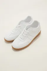 Zapatilla urbana de diseño clásico con capellada blanca y suela de goma color caramelo. Presenta cordones al tono y costuras reforzadas en la puntera.