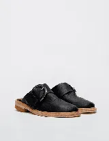 Mules de cuero negro con hebilla plateada y suela color madera.