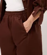 Pantalón palazzo marrón de talle alto y pierna ancha, confeccionado en sarga de algodón y liocel, con cintura elástica y bolsillos laterales.