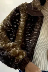 Campera corta de piel sintética con estampado animal print tipo ciervo, cuello clásico, cierre frontal y puños elásticos en cuero sintético.