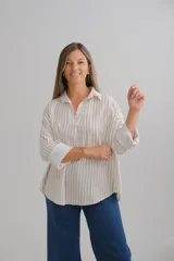 Blusa de corte holgado con estampado de rayas verticales en tonos beige y blanco. Presenta cuello camisero con escote en V, mangas largas con puños anchos y dobladillo redondeado.