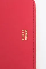 Billetera mediana de estructura rígida en color marrón topo, con cierre perimetral de cremallera y tirador decorativo de cordón. Presenta el logo de la marca aplicado en letras metálicas doradas en el frente.