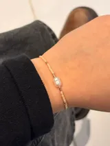 Pulsera de cuentas miyuki beige con una perla de río central y detalles metálicos.