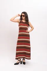 Vestido largo de tejido de punto con patrón en zigzag de rayas en tonos marrón, rojo, negro y beige, sin mangas y con escote redondo.