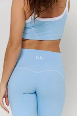 Conjunto deportivo compuesto por un top corto con cuello redondo y ribete blanco, y un pantalón largo de tiro alto con corte acampanado en el bajo.
