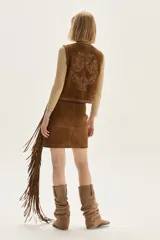 Falda corta de cuero color marrón, con diseño de flecos largos desmontables que cubren toda la prenda. Presenta un estilo western con cierre en la cintura.
