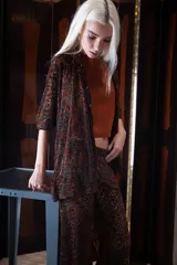 Camisa de corte recto y estructura clásica, confeccionada en una base de encaje con diseño de terciopelo en tono marrón. Presenta cuello camisero, cierre frontal con botones y mangas de largo medio.