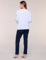 Blusa blanca de silueta semi entallada, confeccionada en tejido texturado. Cuenta con escote en V con abertura y vivo bordado multicolor, mangas 3/4 abullonadas con bordados, calados y puños elásticos.