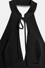 Vestido corto de cuello halter con abertura frontal y lazada, espalda descubierta y falda con bajo acabado en volumen. Cuenta con cierre de cremallera oculto en la espalda y forro interior.