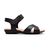 Sandalia casual de cuero sintético negro, con tira ancha sobre el empeine y tira con hebilla ajustable al tobillo.