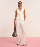 Pantalón de vestir blanco, de corte recto, con trabillas en la cintura, cierre oculto y pliegues.