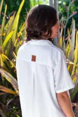 Vestido camisero de muselina color negro, de largo midi, con cuello clásico, manga corta y cierre frontal con botones.