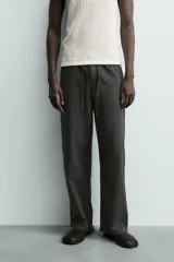Pantalón de corte regular fit confeccionado en mezcla de algodón y lino. Presenta cintura elástica con cordón ajustable, cierre frontal con cremallera y botón, bolsillos laterales y bolsillo trasero de vivo con botón.