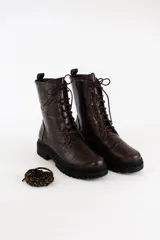 Borcego acordonado de cuero con textura croco, suela track de goma y cierre lateral interno. Incluye cordones intercambiables.