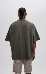 Remera de manga corta color verde militar, con calce extra oversize y un recorte horizontal que atraviesa el pecho y la espalda.