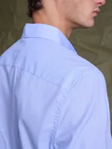 Camisa de vestir manga larga en color celeste, con cuello clásico y cierre frontal de botones. Presenta un corte entallado y puños con botones.