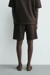 Bermuda estilo jogger de ajuste relajado, color negro, confeccionada en tejido interlock de algodón. Cuenta con cintura elástica ajustable mediante cordón, bolsillos delanteros tipo vivo y diseño liso.
