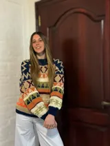 Sweater de lana merino con estampado Fair Isle en tonos azul marino, beige, naranja, verde oliva y bordó. Tiene cuello redondo y mangas largas.