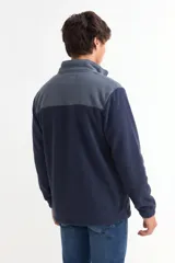 Campera de polar con cierre frontal completo, cuello alto y diseño bicolor en gris y negro. Cuenta con bolsillos laterales y puños elásticos.