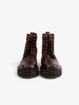 Bota acordonada de caña media, confeccionada en una combinación de cuero liso marrón y paneles laterales con estampado geométrico en tonos marrones. Presenta suela track robusta y negra, con cordones al tono y ojalillos metálicos.