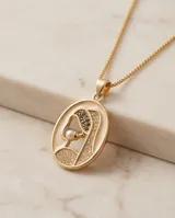 Collar de bronce dorado con cadena fina y dije ovalado con la figura de una virgen incrustada con pequeños cristales y una perla central.