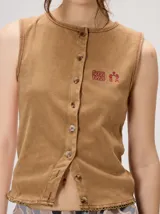 Musculosa MUTMA Trebola de silueta recta confeccionada en tejido de punto color gris con efecto lavado. Posee cierre frontal con botones, detalle de bordado en el pecho y terminación festoneada en el ruedo y las sisas.