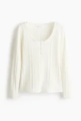 Top de manga larga en punto acanalado de algodón con diseño pointelle, escote en U con ribete festoneado y tapeta con botones al frente.